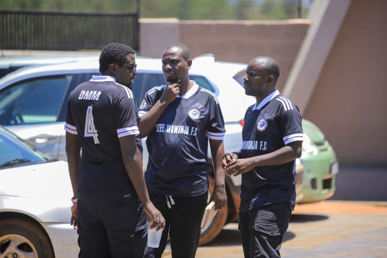Three Mzee Wawanja members talking beside the pitch